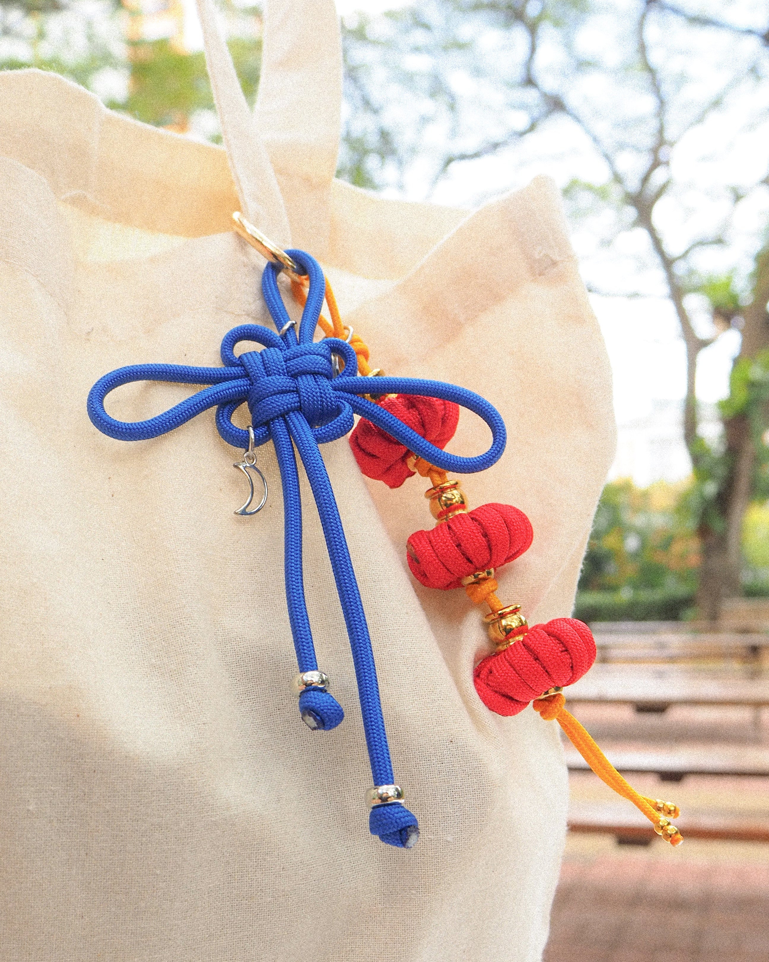 Colorful decorative tassels on a beige bag with a blurred natural background